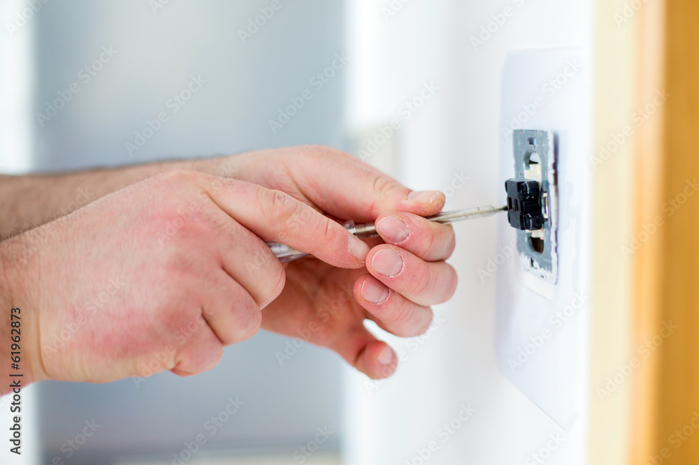 Man installing light switch with screwdriver
