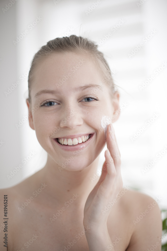 Attractive girl putting anti-aging cream on her face Attractive girl putting anti-aging cream on her face