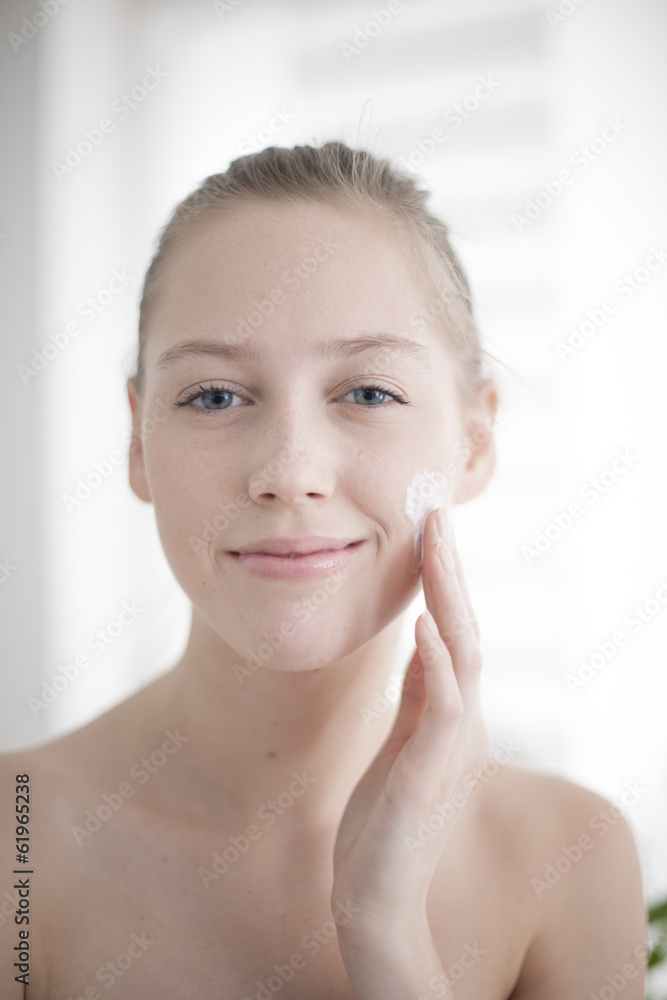 Attractive girl putting anti-aging cream on her face Attractive girl putting anti-aging cream on her face