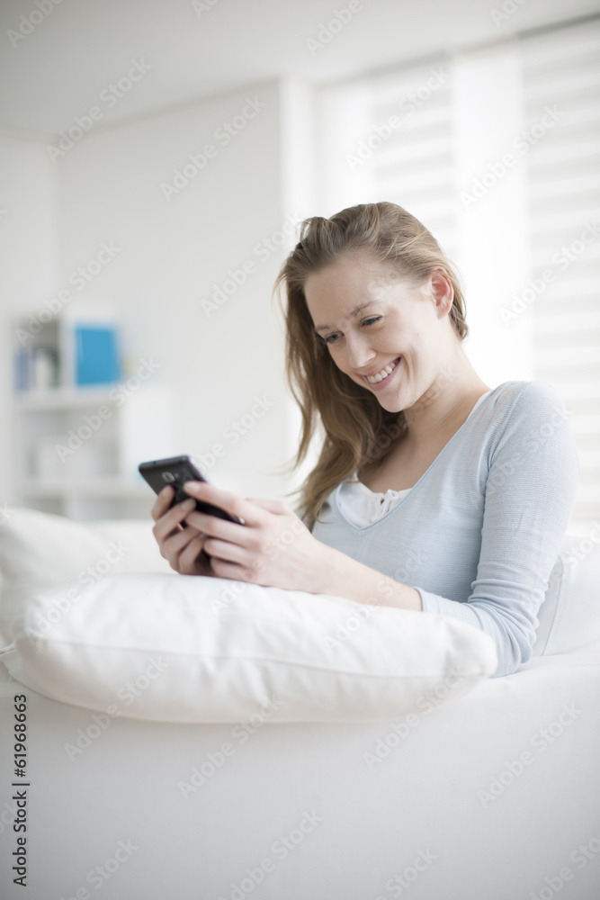 handsome young woman sit in a couch uses her phone to send a mes handsome young woman sit in a couch uses her phone to send a mes