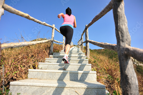 fitness woman running up on mountain stairs to peak