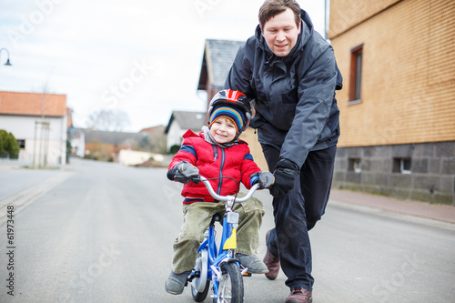 Young father teaching his 3 years old little son to ride a bike © Irina Schmidt