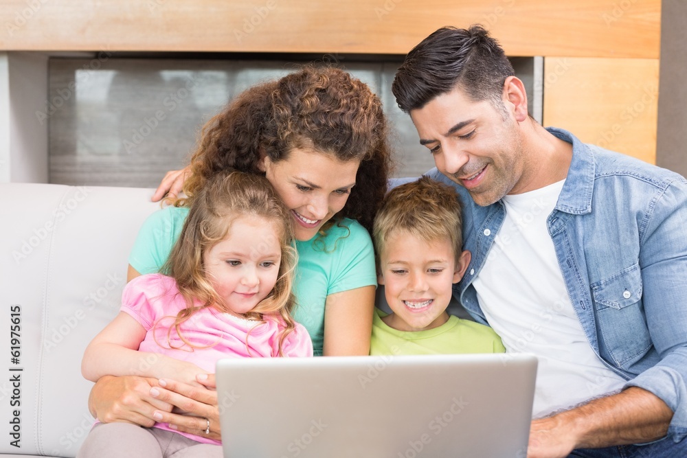 Happy family sitting on sofa using laptop together