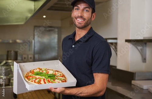 Happy pizza delivery man showing fresh pizza