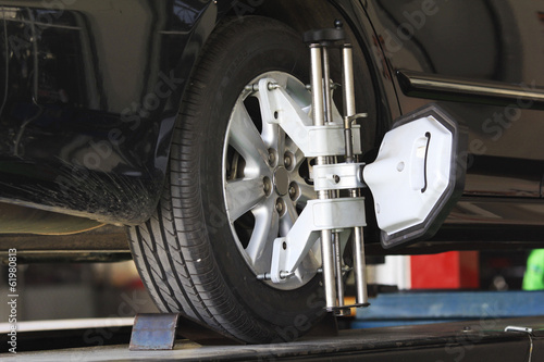 Car wheel fixed with computerized wheel alignment machine clamp. © WS Films