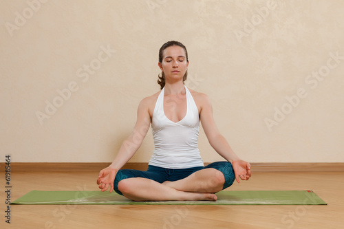 Caucasian woman is practicing yoga at studio (sukkhasana)