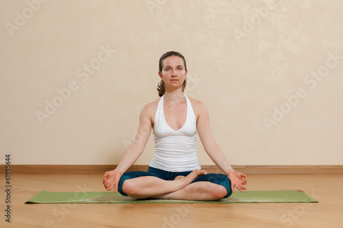 Caucasian woman is practicing yoga at studio (ardkhapadmasana)