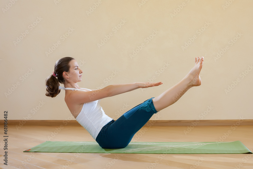 Fototapeta premium Caucasian woman is practicing yoga at studio (paripurna navasana