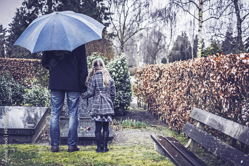 Man with little girl visiting graveyard of deceased wife