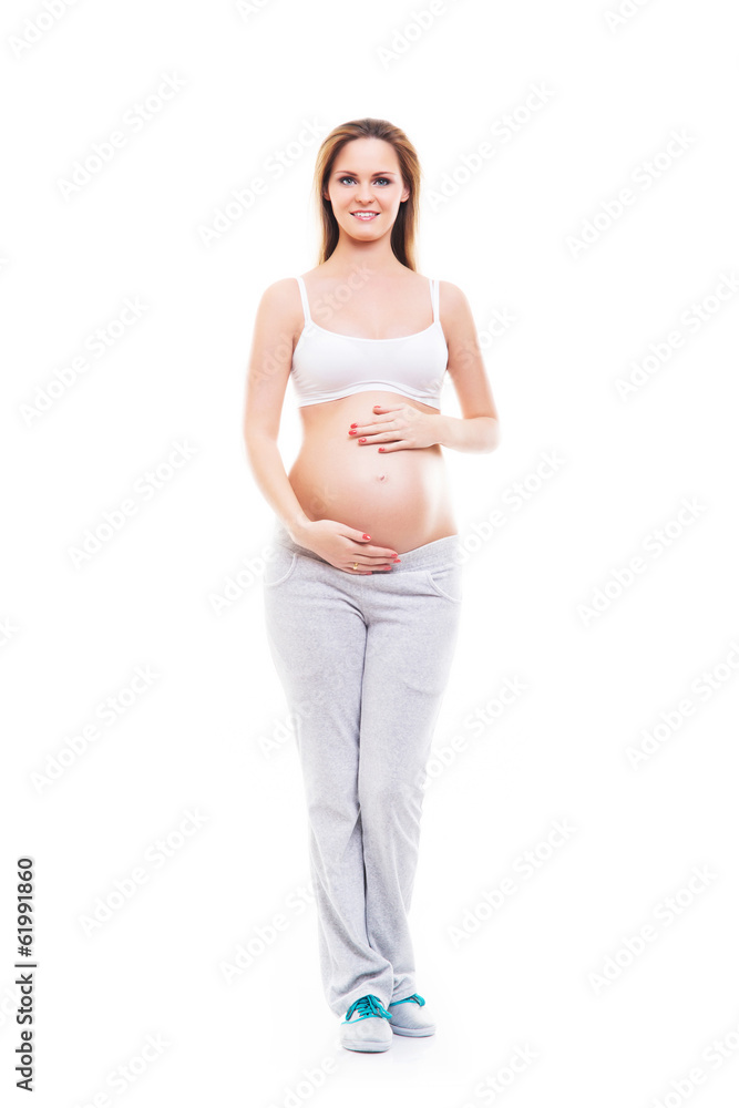 A young and happy pregnant woman posing in white sporty clothes A young and happy pregnant woman posing in white sporty clothes