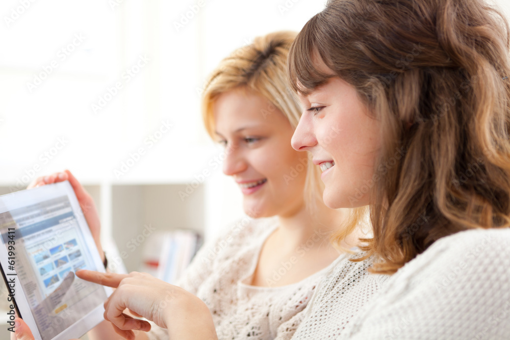 Girls choosing their holidays destination on tablet Girls choosing their holidays destination on tablet