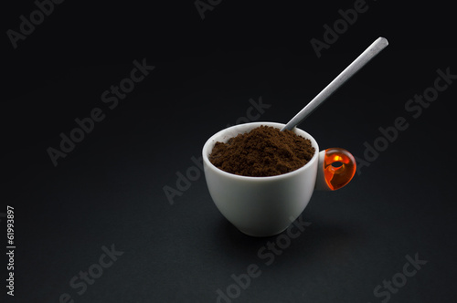 cup of coffee with minced coffee on black background