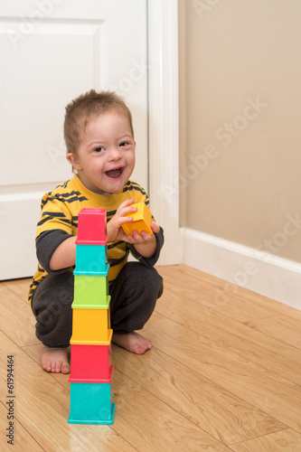 фотографія Laughing Down Syndrome boy plays with stacking toy