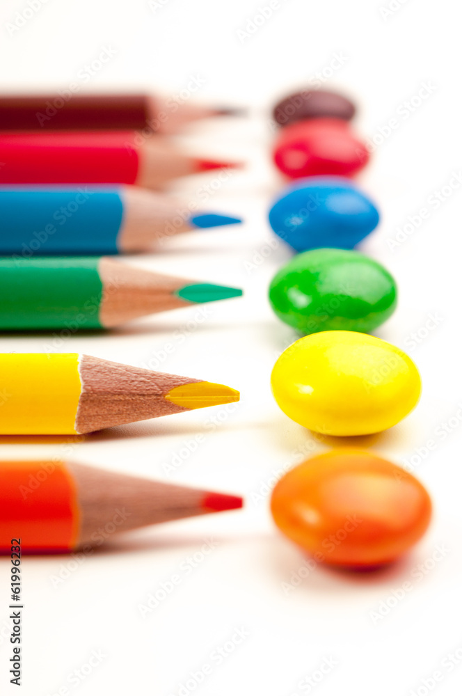 Closeup photo of pencils pointing at the same color candies Closeup photo of pencils pointing at the same color candies