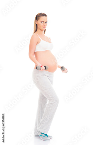 A young and pregnant blond woman working out with dumbbells