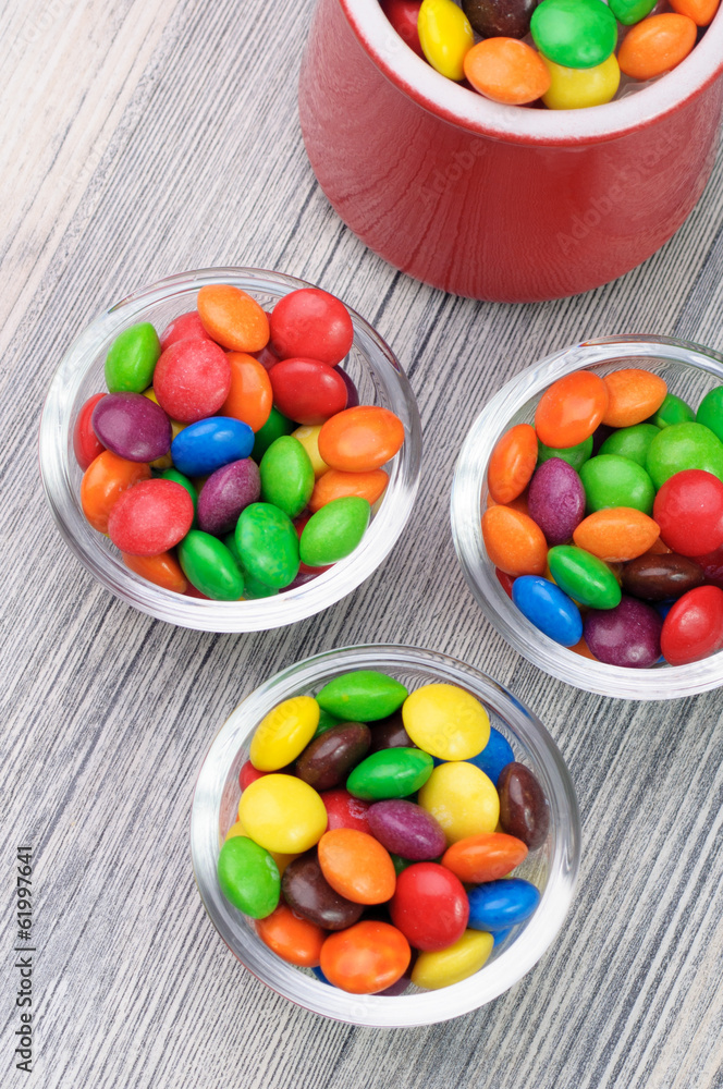 Three little bowls with vibrant candies and a red jar Three little bowls with vibrant candies and a red jar