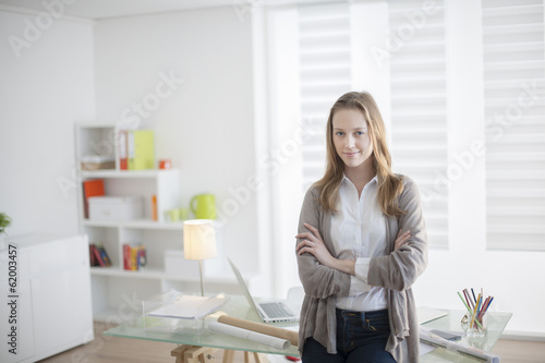 beautiful young woman arms crossed standing in front of his desk
