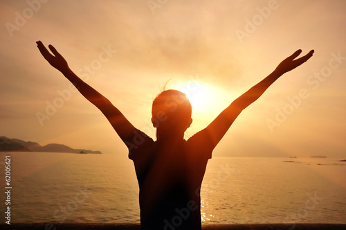 cheering woman open arms to sunrise seaside