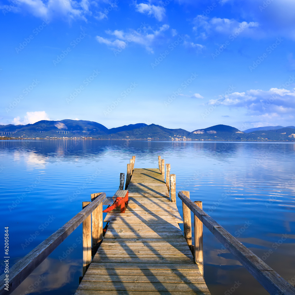 Obraz premium Wooden pier or jetty on a blue lake sunset and sky reflection on