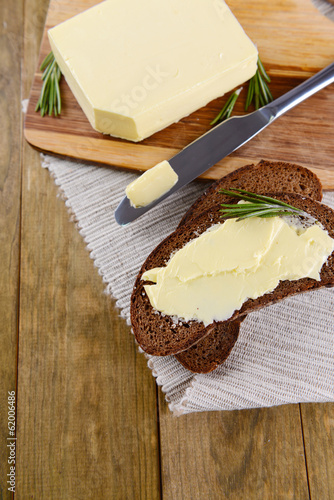 Slice of rye bread with butter on wooden cutting board