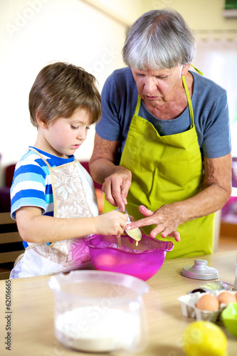 Senior woman helping grandson to cook and bake