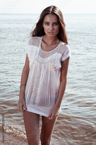 Young sexy brunette on the beach in wet t-shirt