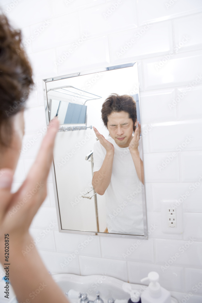 Fototapeta premium man patting face lotion on cheek