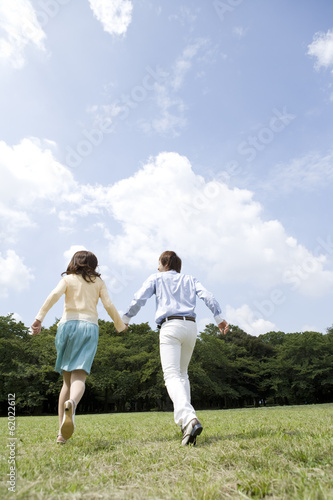 couple holding hands run on lawn