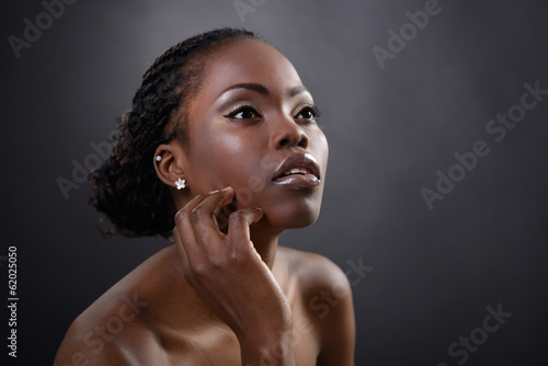 Beautiful young african woman posing at studio, face with hand p