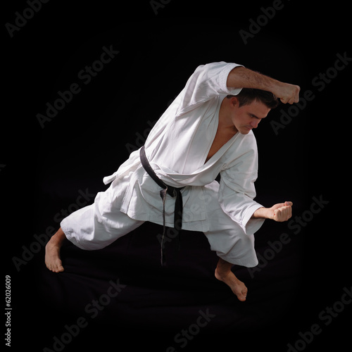 karate man with black belt posing, champion of the world on blac