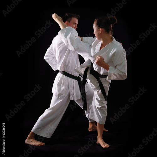 fighting karate couple, man and woman with black belts - champio