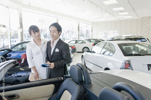 husband and wife looking at cars in showroom