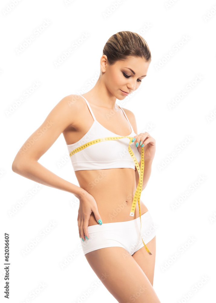 A fit and beautiful girl with a measuring tape isolated on white A fit and beautiful girl with a measuring tape isolated on white