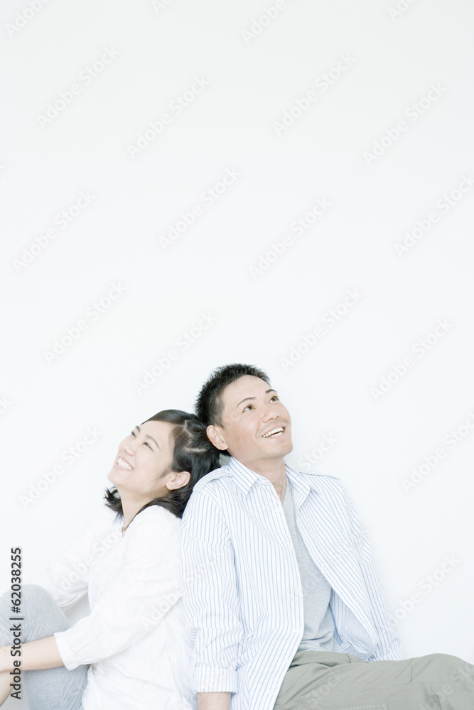 smiling couple sitting back to back smiling couple sitting back to back