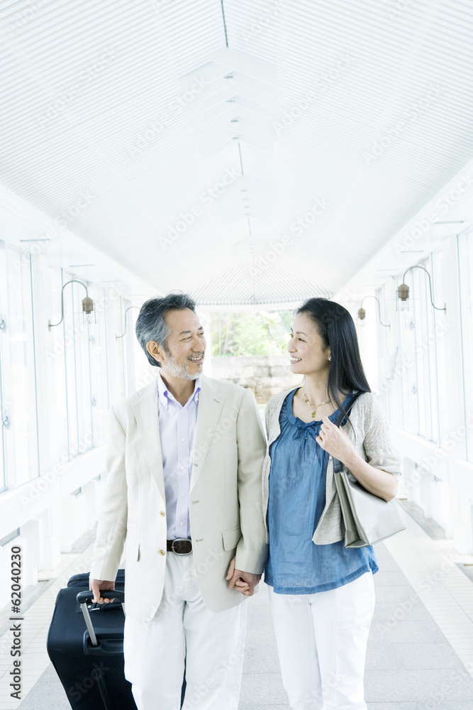 husband and wife holding hands and walking with suitcase husband and wife holding hands and walking with suitcase