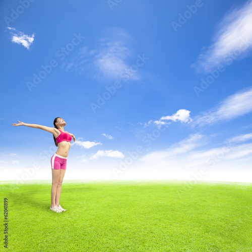 relaxing young woman standing on a meadow with blue sky
