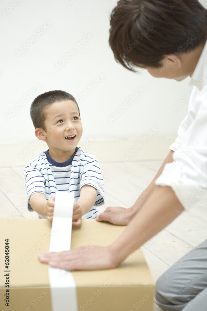father and son taping on cardboard box father and son taping on cardboard box