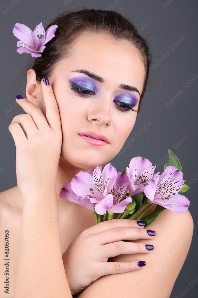 Beautiful young woman with flowers on gray background Beautiful young woman with flowers on gray background