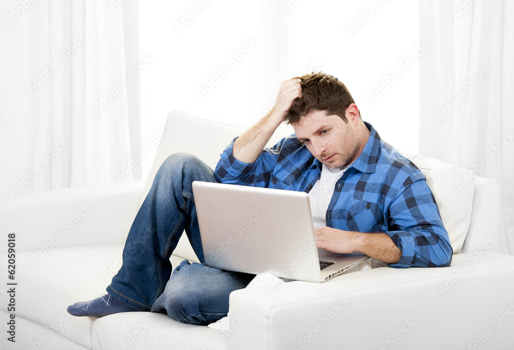 Worried Attractive man with computer sitting on couch Worried Attractive man with computer sitting on couch