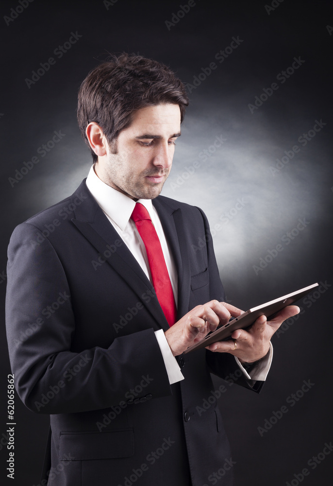 Businessman working on a digital tablet against black background Businessman working on a digital tablet against black background