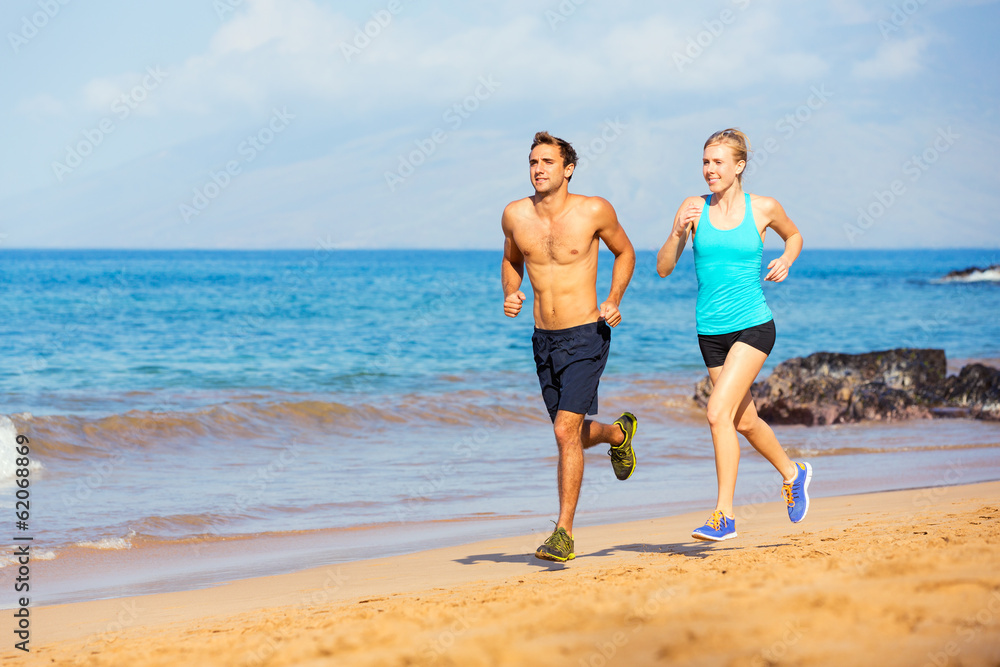 Sporty couple jogging together on the beach Sporty couple jogging together on the beach