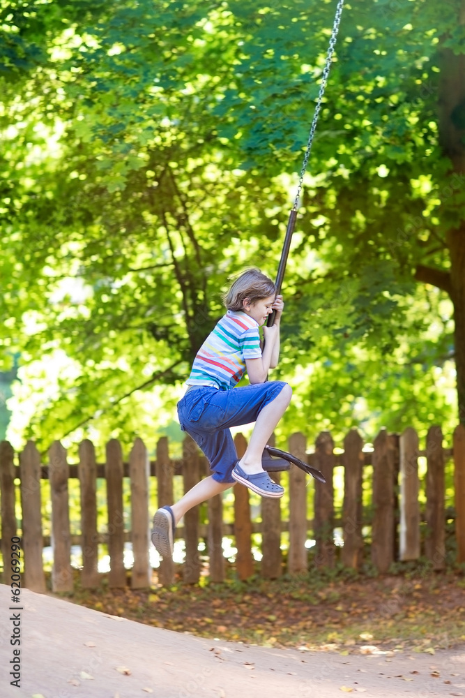 Funny little boy enjoying a swing ride on a playground Funny little boy enjoying a swing ride on a playground