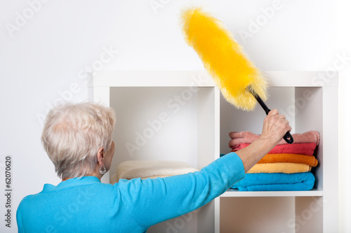 Photography Elderly lady during dusting furniture