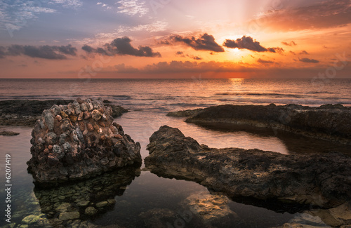 Sunset over the Sea and Rocky Coast with Ancient Ruins