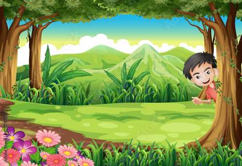 A smiling boy playing hide and seek at the forest