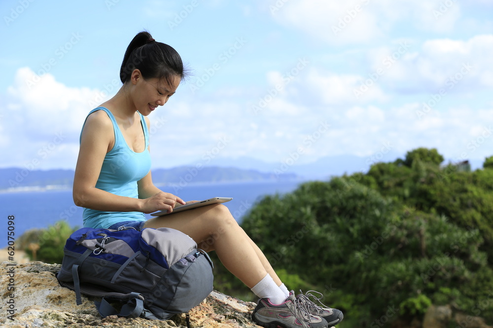 woman hiker use digital tablet on seaside mountain peak
