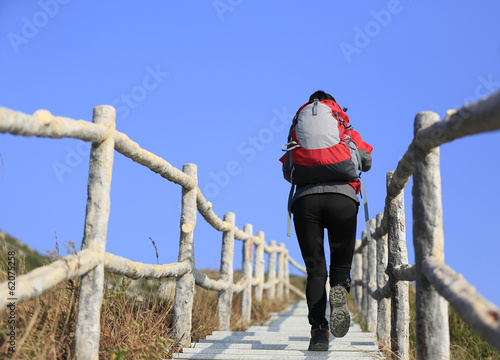 woman hiker climbing stairs to mountain peak