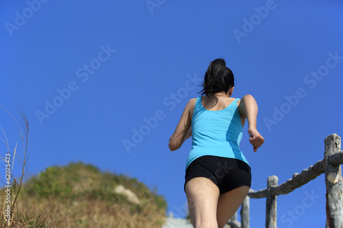 young sporty woman running up on stairs to the mountain peak