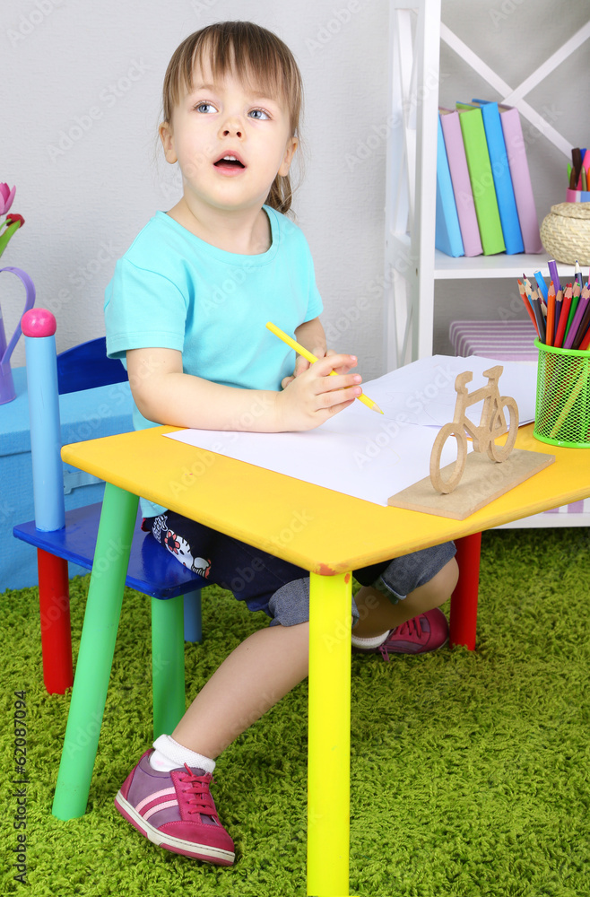 Little girl draws sitting at table in room Little girl draws sitting at table in room