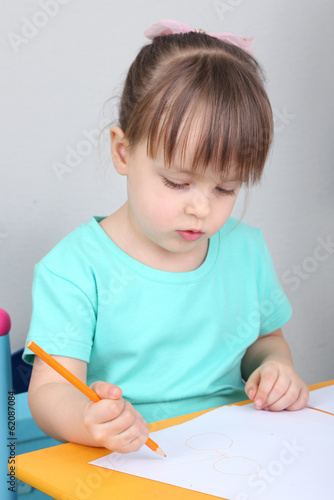 Little girl draws sitting a...